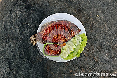 Delicious grilled tilapia nila bakar from indonesia with rice, tempeh, vegetables, and chilli sauce in plate Stock Photo