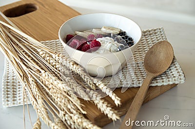 Delicious healthy breakfast of cottage cheese with berries. A white plate with cottage cheese and berries stands on a wooden board Stock Photo