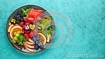 Delicious healthy salad of fresh fruits, berries and edible flowers on plate. Clean eating. Top view Stock Photo