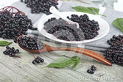 Delicious homemade black elderberry syrup and bunches of black elderberry with green leaves on wooden desk. Elderberry syrup Stock Photo
