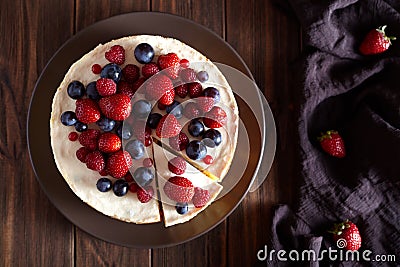 Delicious Homemade creamy mascarpone New York Cheesecake with berries on dark wooden table. Top viev. Stock Photo