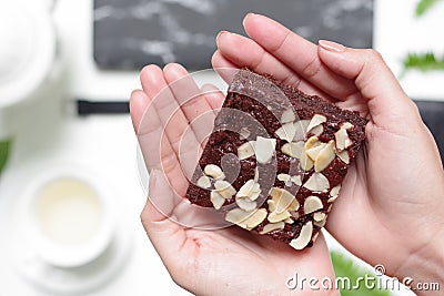 A delicious homemade nutty brownie with earl grey in the afternoon tea time. On beautiful hands. Stock Photo