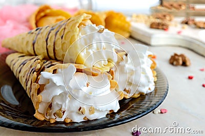 Delicious honeyed waffles, twisted into cones with cream, nuts, chocolate topping on the plate Stock Photo