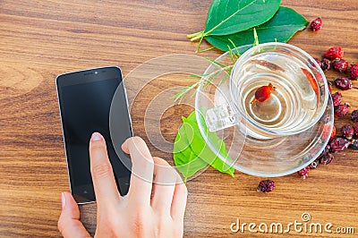 Delicious hot tea and mobile phone on table Stock Photo