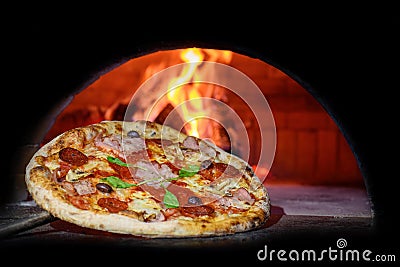 Delicious Italian pizza in a shovel putting in wood burning oven Stock Photo