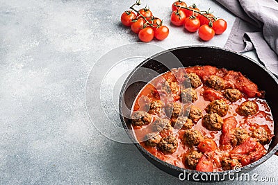 Delicious juicy Meatballs in tomato sauce are cooked in a castiron pan. Concrete background. Copy space Stock Photo