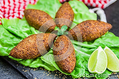 Delicious Lebanese food, kibbeh kibe with sauces and lemon on black slate stone and granite background with traditional keffyeh Stock Photo