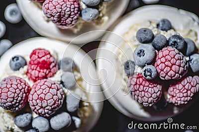 Delicious mini pavlova meringue desserts served with frozen frosty berries and mascarpone whipped cheese Stock Photo