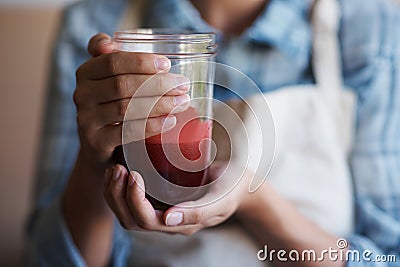 Delicious and nutritious. A cropped shot of a young woman holding a glass of freshly squeezed juice. Stock Photo