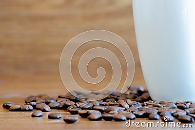 Delicious organic and roasted coffee beans on wooden table next to white cup Stock Photo