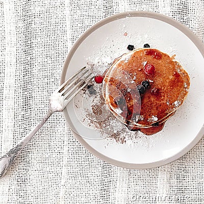 Delicious pancakes with syrup and berries on stylish plate on rustic table with vintage fork, flat lay. Yummy homemade breakfast. Stock Photo
