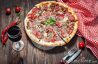 Delicious pizza, glass of wine vegetables and spices on wooden table Stock Photo