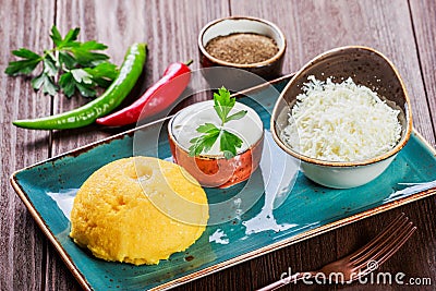 Delicious polenta - Corn porridge hominy with goat cheese, butter and sour cream on wooden background. Healthy food. Stock Photo