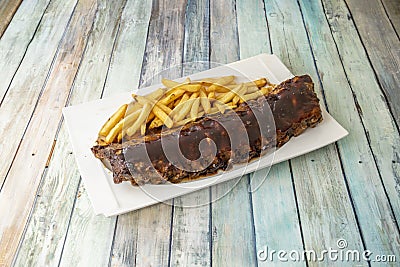 Delicious pork ribs marinated with barbecue sauce garnished with French fries Stock Photo