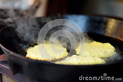 Delicious potato pancakes being fried on spring market in Vilnius, Lithuania. Variety tasty street food on Easter fair Stock Photo