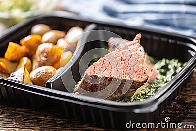 Delicious red meat sous vide steak packed in portable take away plastic box and served with crunchy roasted potatoes and savory Stock Photo