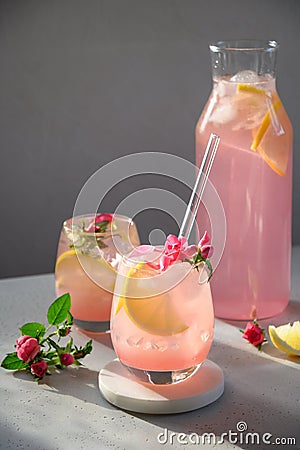 Delicious refreshing drink with lemon and roses with sunny shadow on gray background. Close up Stock Photo