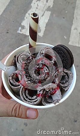 Delicious rolled ice cream with chocolate, oreo cookie and strawberry sauce in a cup Stock Photo