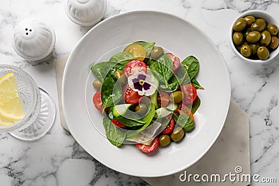 Delicious salad with vegetables and olives served on white marble table, flat lay Stock Photo