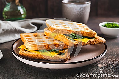 Delicious sandwich of waffle toasts with melted cheese and herbs on a plate Stock Photo