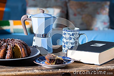 Delicious slice of Easter cake, good book and hot coffee on old, dark wooden table - perfect easy morning during stay at home Stock Photo