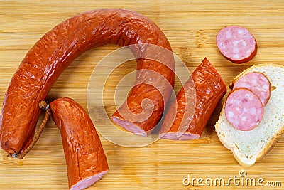 Delicious sliced smoked sausage on bread with bamboo cuting board Stock Photo