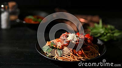 Delicious spaghetti served on a black plate with dark dining background Stock Photo