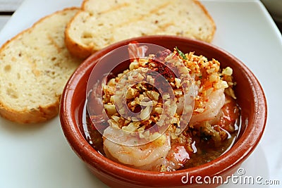 Delicious Spanish Style Garlic Shrimp or Gambas al Ajillo with Blurry Sliced Breads in Background Stock Photo