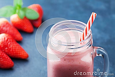 Delicious strawberry smoothie or milkshake in mason jar on dark blue table. Healthy food for breakfast and snack. Stock Photo