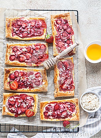 Delicious sweet sliced pies with strawberry. Puff pastry mini pies with strawberry, cream cheese, almond and honey. Top view Stock Photo