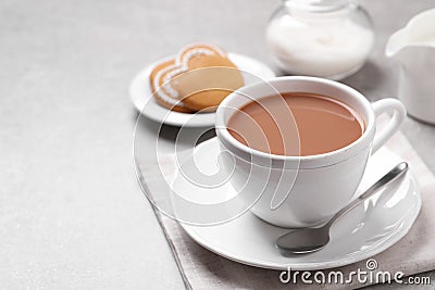 Delicious tea with milk in white cup near cookies on grey table, space for text Stock Photo