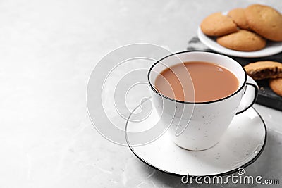 Delicious tea with milk in white cup near cookies on grey table. Space for text Stock Photo