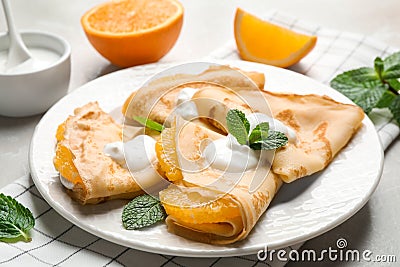Delicious thin pancakes with oranges and cream on table Stock Photo