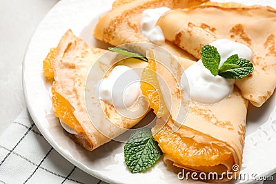 Delicious thin pancakes with oranges and cream on table, closeup Stock Photo