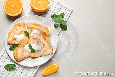 Delicious thin pancakes with oranges and cream on marble table, flat lay. Space for text Stock Photo