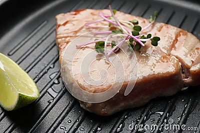 Delicious tuna steak with lime and microgreens in grill pan, closeup Stock Photo