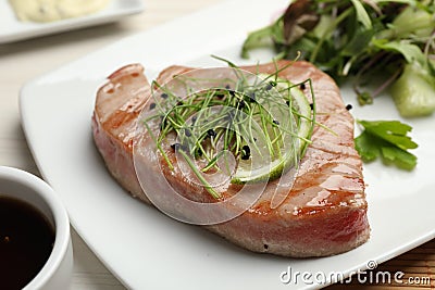Delicious tuna steak with microgreens and lime on plate, closeup Stock Photo