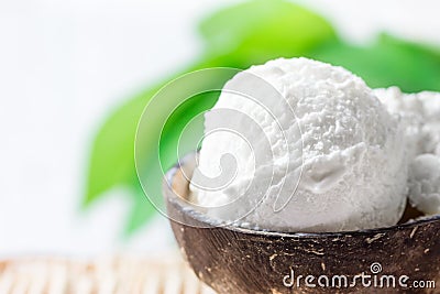 Delicious Vegan Coconut Ice Cream in Bowl on Wicker Table. Green Palm Leaves Tropical Plants Background. Plant Based Diet Stock Photo