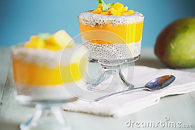 Delicious vegan mango chia pudding with fresh mint springs in a glass jar on a green wooden background Stock Photo