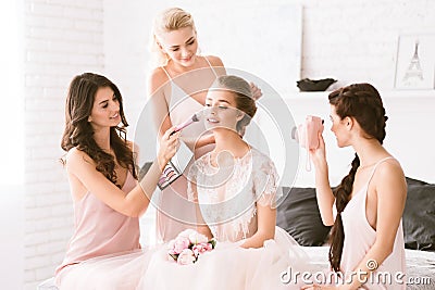 Delighted bridesmaids helping the bride to get ready Stock Photo