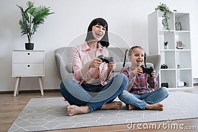 Parent and daughter playing video game with joypads on floor Stock Photo