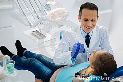 Delighted positive dentist doing his duties Stock Photo