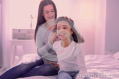 Delighted positive girl sitting in front of her mother Stock Photo