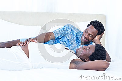 Delighted pregnant woman lying on bed with her husband Stock Photo