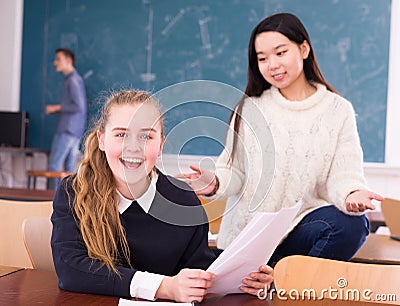 Delighted schoolgirl and Chinese girl schoolmate reading notification Stock Photo