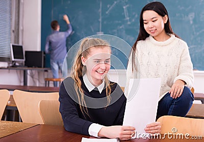 Delighted schoolgirl and Chinese girl schoolmate reading notification Stock Photo