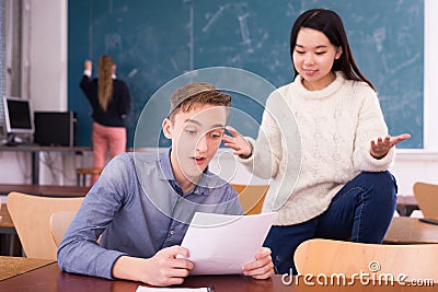 Delighted teenager and Chinese girl schoolmate reading notification Stock Photo