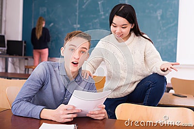 Delighted teenager and Chinese girl schoolmate reading notification Stock Photo