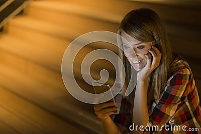 Delighted young woman reading an sms on her mobile phone smiling Stock Photo