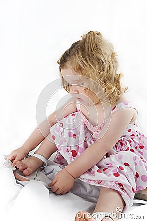 Delightful baby girl untying her shoe. Stock Photo
